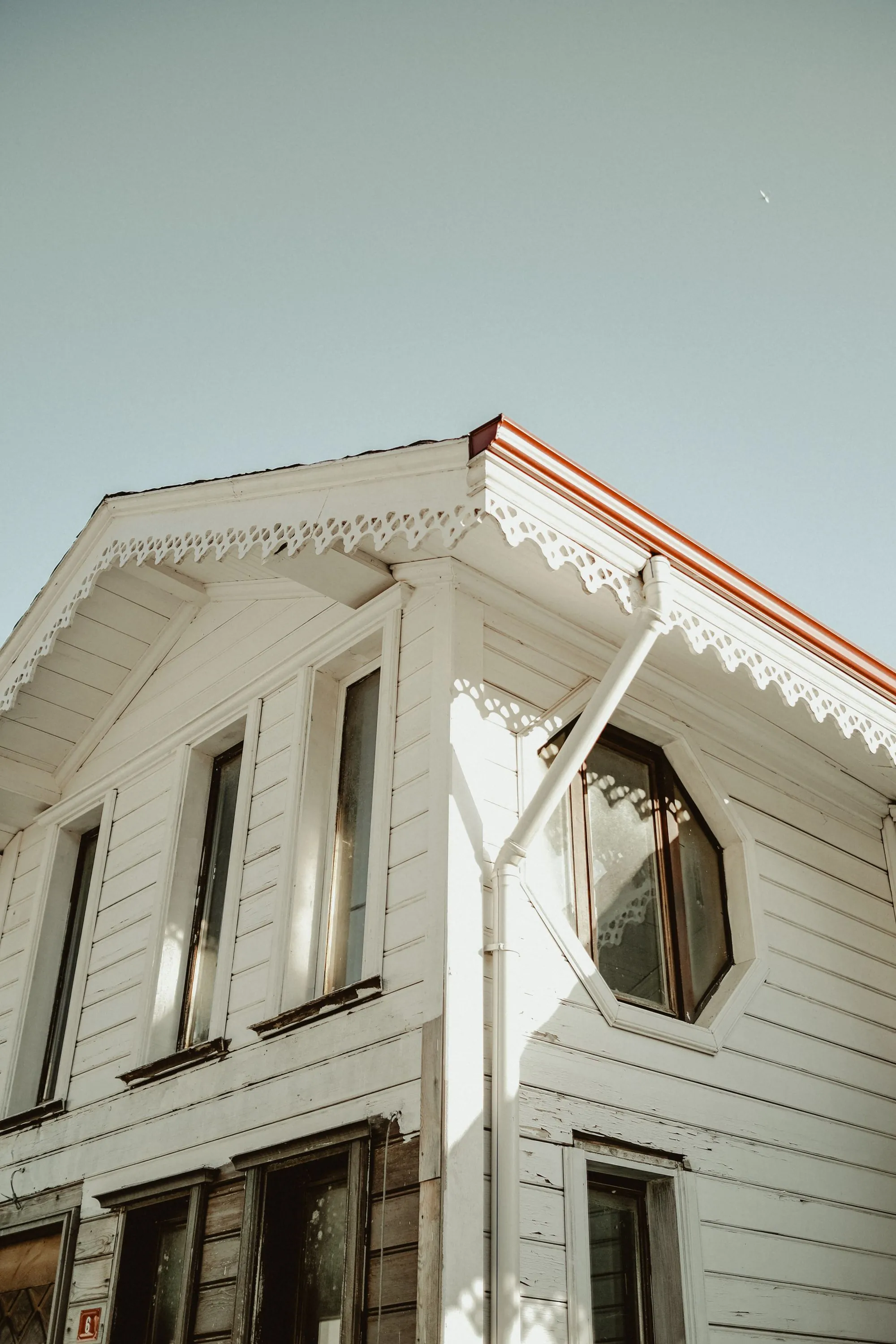 The gable end of a white house with decorative trim under the eaves