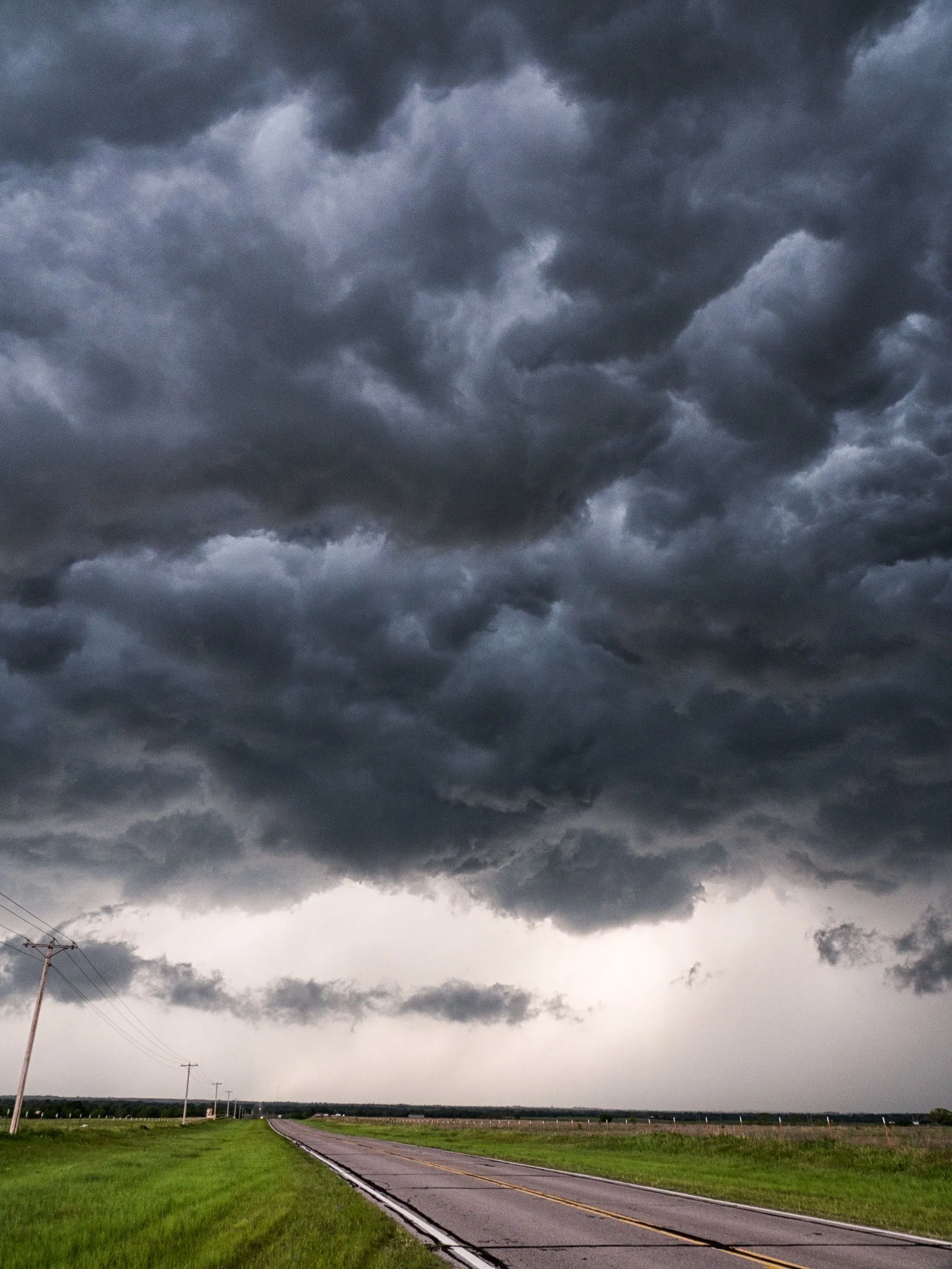 A heavy bank of storm cloud rolling in low over open ground
